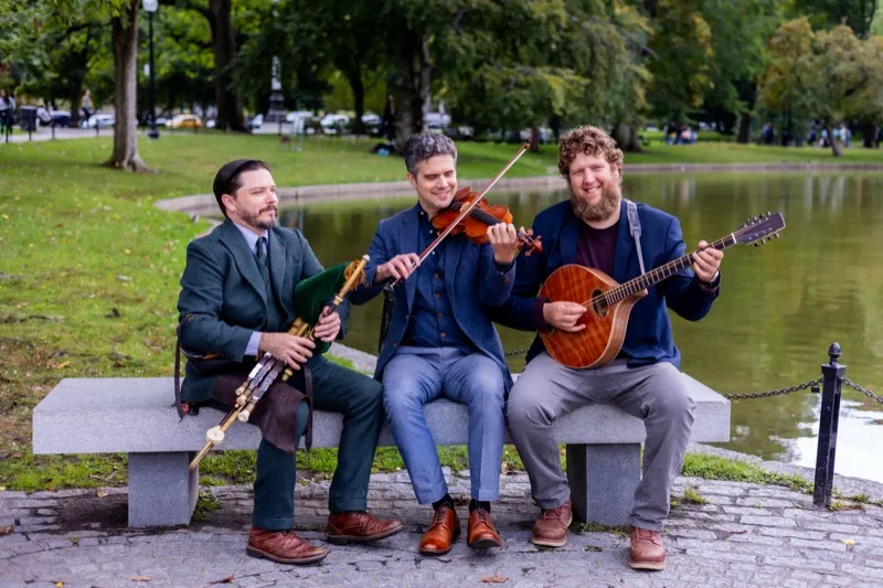 Joey Abarta, Nathan Gourley, and Owen Marshall playing on a park bench in the Boston Public Garden