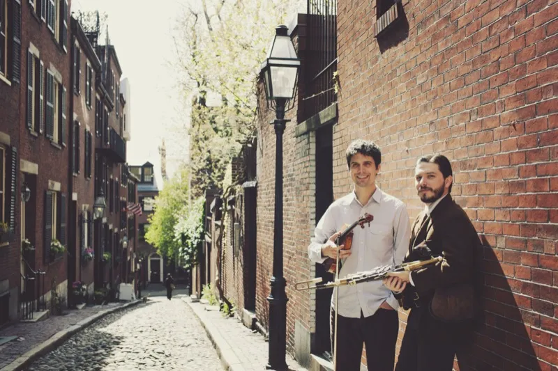 Nathan Gourley and Joey Abarta on a cobblestone street with instruments